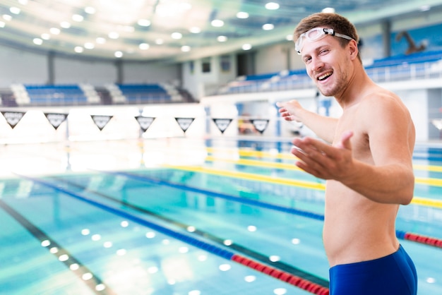 Einladender Fotograf des männlichen Schwimmers des smiley zum Schwimmen