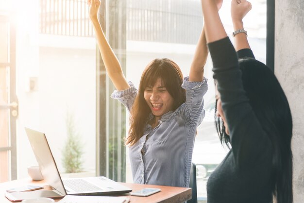 Eins-zu-Eins-Treffen. Zwei junge Geschäftsfrauen, die am Tisch im Café sitzen. Mädchen zeigt Kollegeninformationen über Laptopbildschirm. Mädchen, welches den Smartphone Blogging verwendet. Teamwork-Geschäftstreffen. Freiberufler arbeiten.