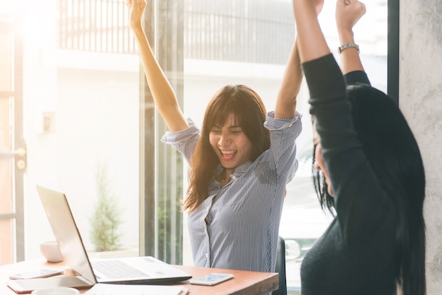 Eins-zu-Eins-Treffen. Zwei junge Geschäftsfrauen, die am Tisch im Café sitzen. Mädchen zeigt Kollegeninformationen über Laptopbildschirm. Mädchen, welches den Smartphone Blogging verwendet. Teamwork-Geschäftstreffen. Freiberufler arbeiten.