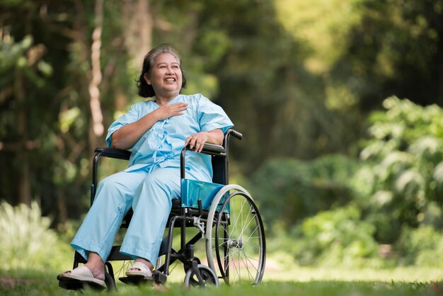 Einsame ältere Frau, die trauriges Gefühl auf Rollstuhl am Garten im Krankenhaus sitzt