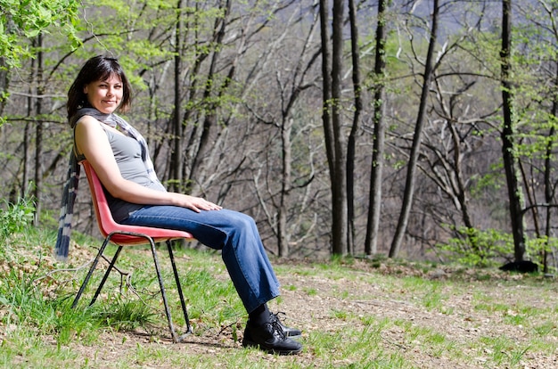 Kostenloses Foto einsame frau, die auf einem stuhl sitzt und sich in einem park entspannt