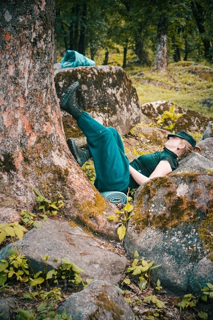 Einsame junge Frau, die an einem Baum und neben Felsformationen schläft