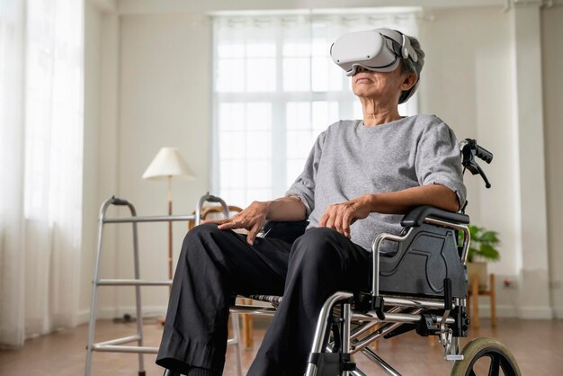 Einsamer älterer männlicher Mann im Rollstuhl gestikuliert und konzentriert sich beim Tragen der Virtual-Reality-Brille zu Hause im Wohnzimmer Aufnahme eines älteren Mannes im Rollstuhl mit VR-Headset