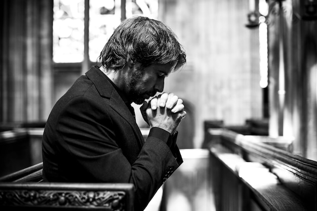 Kostenloses Foto einsamer christlicher mann, der in der kirche betet