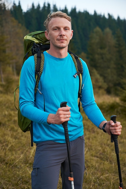 Einsamer junger Mann, der draußen mit Rucksack wandert