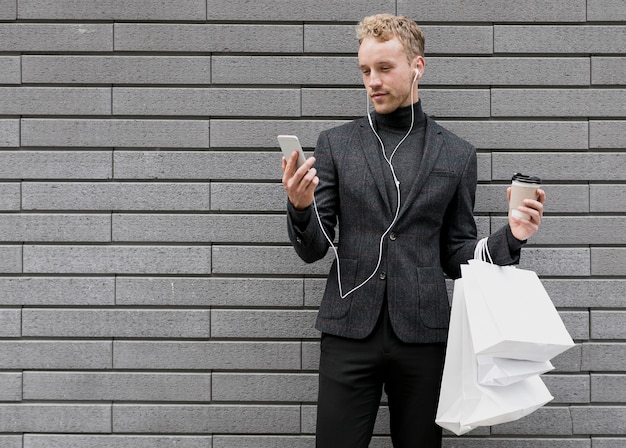 Einsamer Mann mit Einkaufstaschen lächelnd am Smartphone