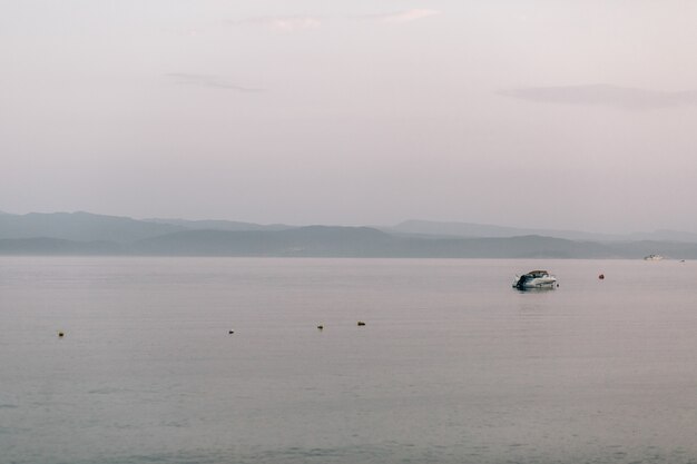 Einsames Boot schwimmt im Meer unter grauem Himmel