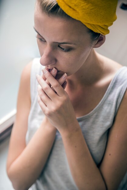 Einsames Mädchen in der Nähe von Fenster über etwas denken. Melancholische Reflexion des Mädchens im Fenster. Schönes Mädchen stand am Fenster und beobachtete. Schöne traurige einsame Mädchen sitzt in der Nähe des Fensters fehlt