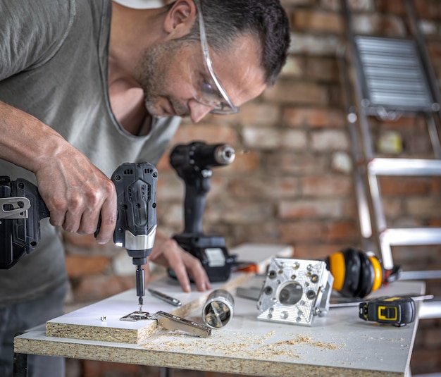 Einschrauben einer selbstschneidenden Schraube in ein Metallbefestigungsloch an einer Holzleiste mit einem Schraubendreher, die Arbeit eines Zimmermanns.