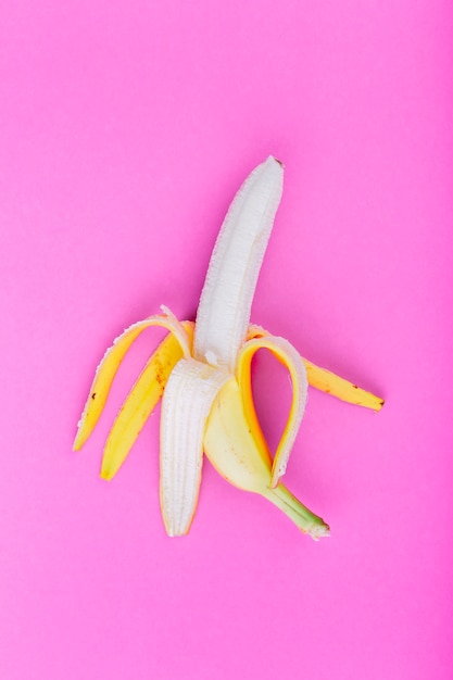 Einzelne abgezogene Banane auf rosafarbenem Hintergrund