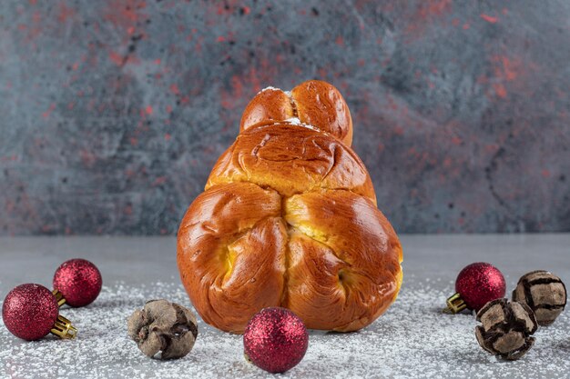 Einzelne Brötchen stehen aufrecht in einem Kreis von Weihnachtsschmuck auf Marmortisch.