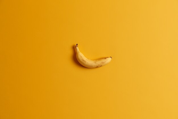Einzelne reife köstliche gelbe Banane lokalisiert über Studiohintergrund. Helle Farbe herrscht vor. Tropische Früchte für Ihren leckeren Snack. Appetitliches essbares Produkt. Leerer Platz für Text oder Informationen