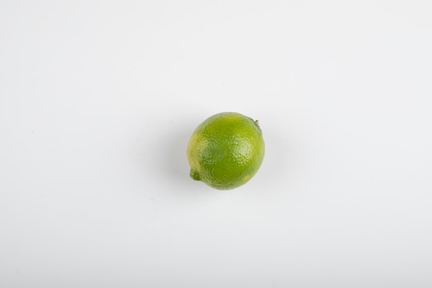 Einzelne reife Limettenfrucht lokalisiert auf weißem Tisch.