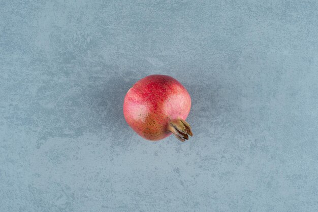 Einzelner roter Granatapfel auf Marmor.