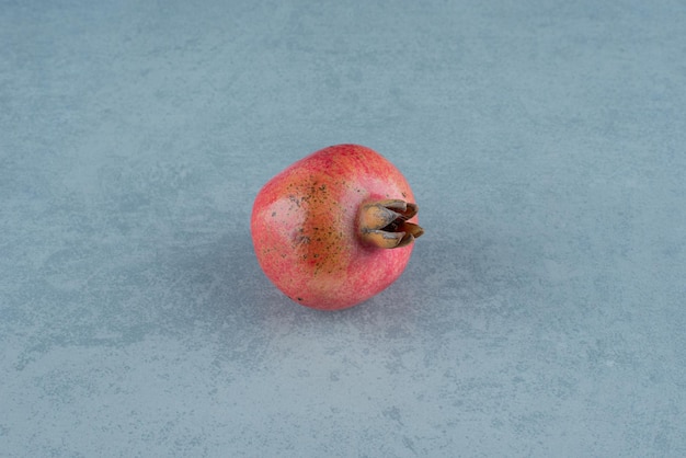 Kostenloses Foto einzelner roter granatapfel auf marmor.