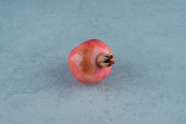 Einzelner roter Granatapfel auf Marmor.