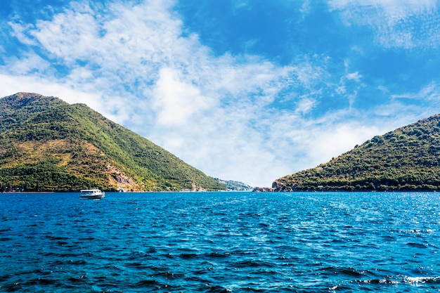 Einzelnes Boot über dem blauen ruhigen See nahe dem grünen Berg