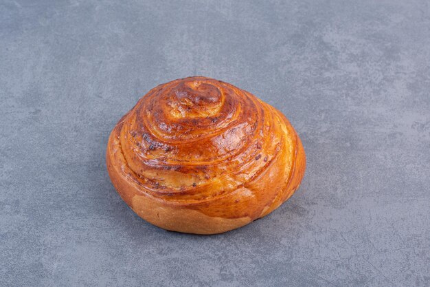 Einzelnes, knuspriges süßes Brötchen auf Marmorhintergrund. Foto in hoher Qualität