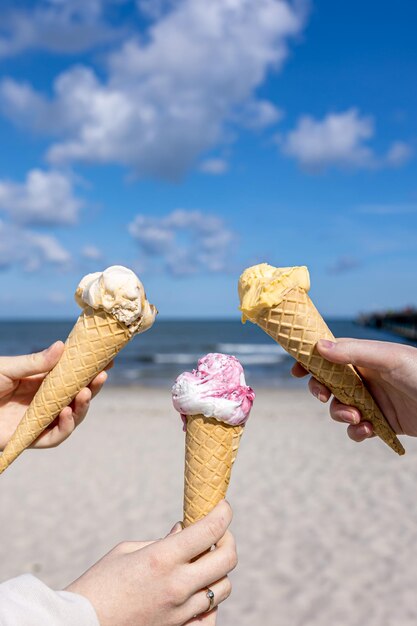 Eis in Waffelkegeln in weiblichen Händen auf dem Hintergrund des Meeres