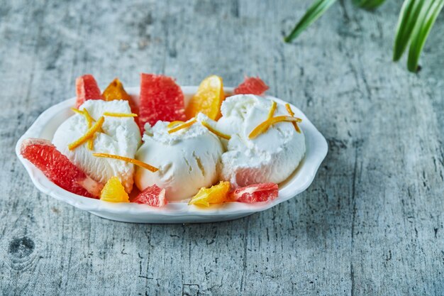 Eis mit Grapefruit und Orangenscheiben in weißer Schüssel. Nahansicht