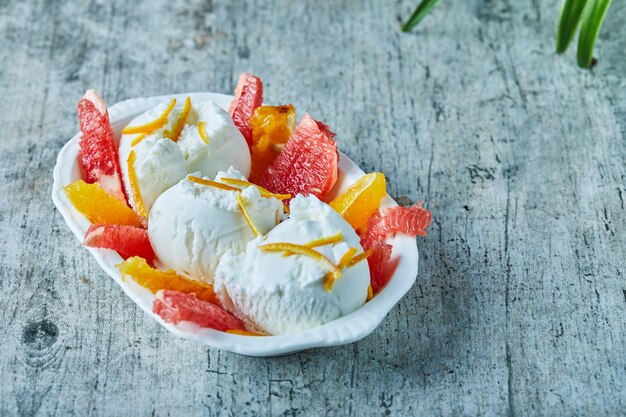 Eis mit Grapefruit und Orangenscheiben in weißer Schüssel