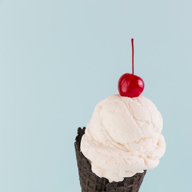 Eiscreme im schwarzen Kegel mit Kirsche oben