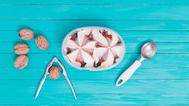 Eiscreme in der Plastikschüssel mit Löffel und Walnüssen mit Nussknacker