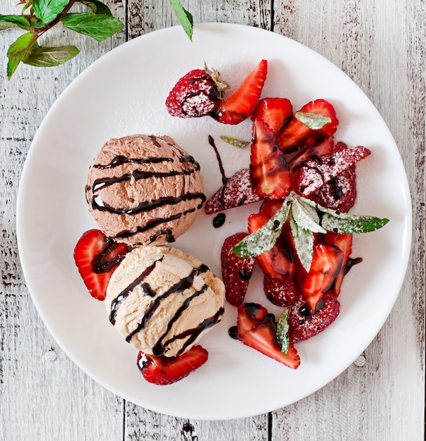 Eiscreme mit Erdbeeren und Schokolade auf einer weißen Platte