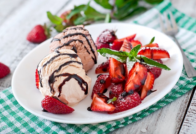 Eiscreme mit erdbeeren und schokolade auf einer weißen platte