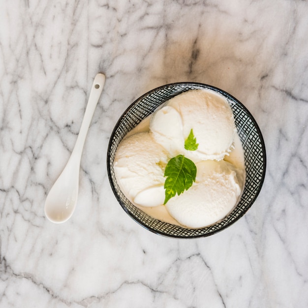 Eiscremekugeln in der Schüssel nahe Löffel