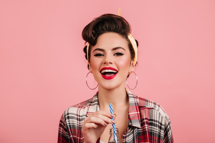 Kostenlose Foto ekstatisches brünettes mädchen, das getränk trinkt. studioaufnahme der eleganten pinup-frau lokalisiert auf rosa hintergrund.
