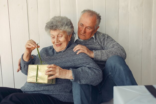 Elegante alte Paare, die zu Hause mit Weihnachtsgeschenken sitzen