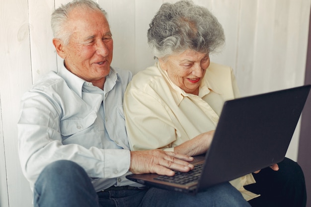 Elegante alte Paare, die zu Hause sitzen und einen Laptop verwenden