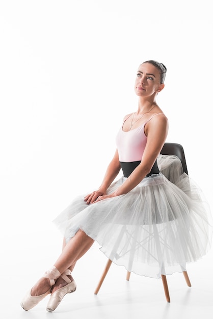 Elegante Ballerina, die auf dem träumenden Stuhl sitzt