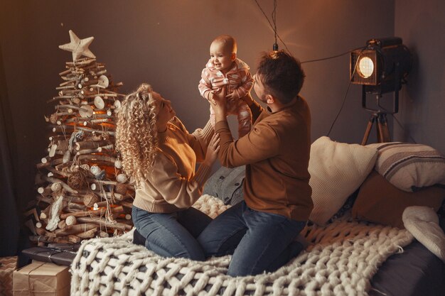 Elegante Familie, die zu Hause nahe Weihnachtsbaum sitzt