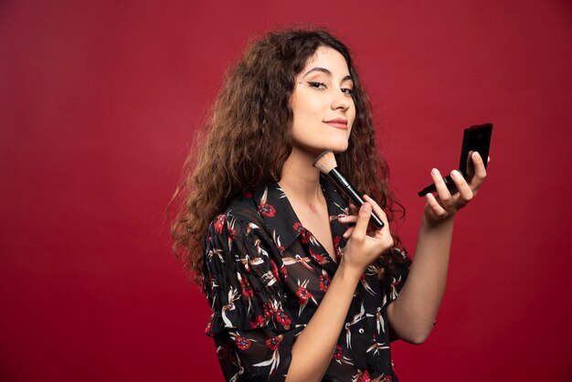 Elegante Frau, die Bronzer mit Pinsel anwendet.