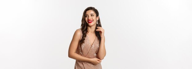 Elegante Frau, die in Abendkleid und Make-up steht, lacht und das neue Jahr mit Outfit feiert