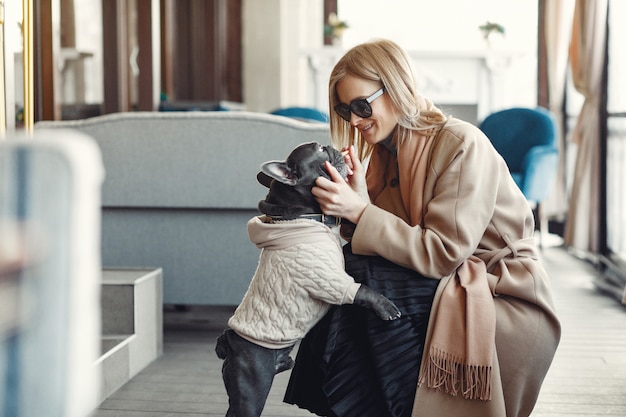 Elegante Frau in einem braunen Mantel mit schwarzer Bulldogge