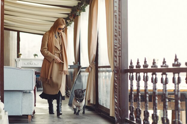 Elegante Frau in einem braunen Mantel mit schwarzer Bulldogge