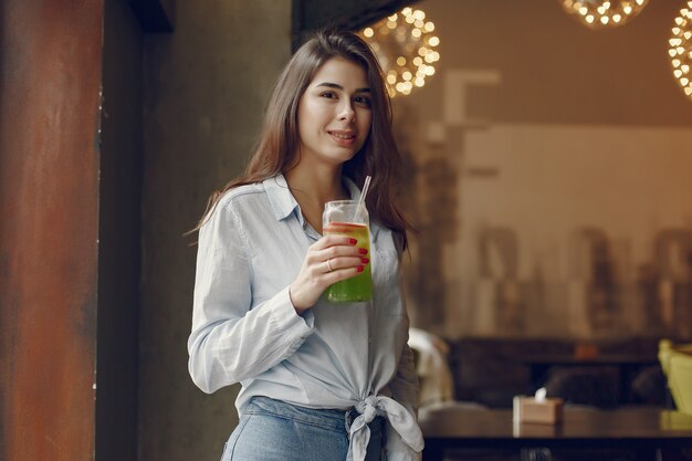 Elegante Frau in einer blauen Bluse, die Zeit in einem Café verbringt