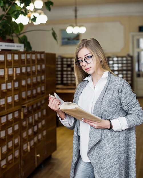 Kostenloses Foto elegante frau mit dem buch, das kamera betrachtet