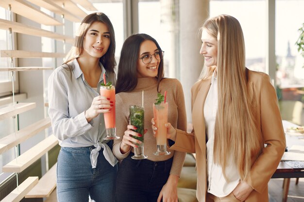 Elegante Frauen, die in einem Café stehen und einen Cocktail trinken