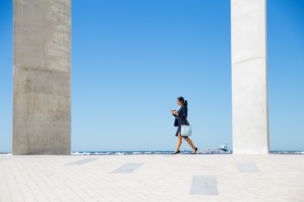 Elegante Geschäftsfrau, die entlang Promenade geht