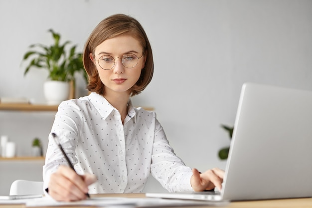 Elegante geschäftsfrau gekleidet formell sitzend mit laptop