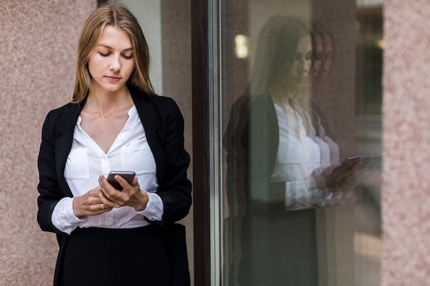 Elegante junge Frau, die ihr Telefon verwendet