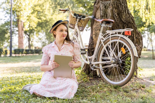 Elegante junge Frau, die mit Fahrrad aufwirft