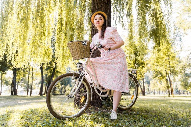 Elegante junge Frau, die mit Fahrrad aufwirft