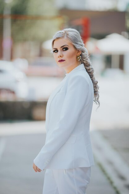 Elegante, modische kaukasische Frau in einem hübschen weißen Anzug und Hosen, die für ein Mode-Fotoshooting posieren