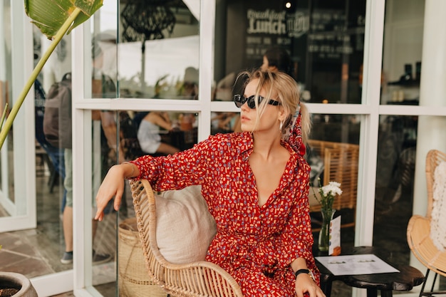 Elegante stilvolle Dame, die im Straßencafé sitzt und auf Freunde an einem guten sonnigen Tag wartet