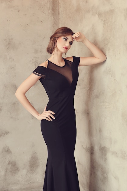 Elegante und glamouröse Frau mit schwarzem Kleid posiert, Modekonzept
